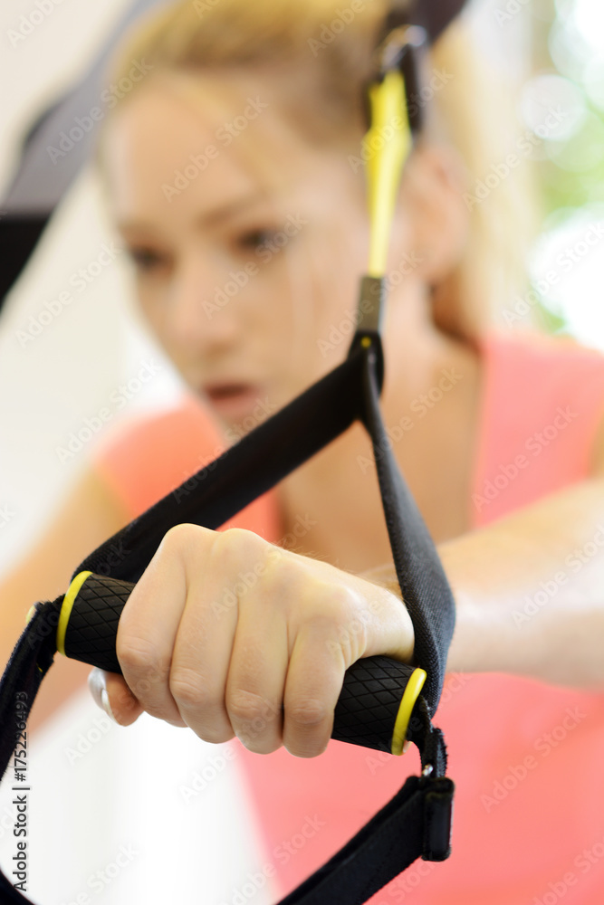 Frau im Fitnessstudio bei Training und Übung mit TRX-Bändern