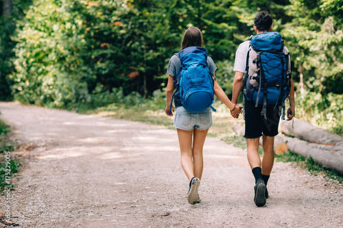 Hiking couple. Young couple with backpacks walking through the forest   © Astarot