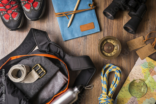 Overhead view of travel equipment for a backpacking trip on wooden floor. Adventure travel concept.
