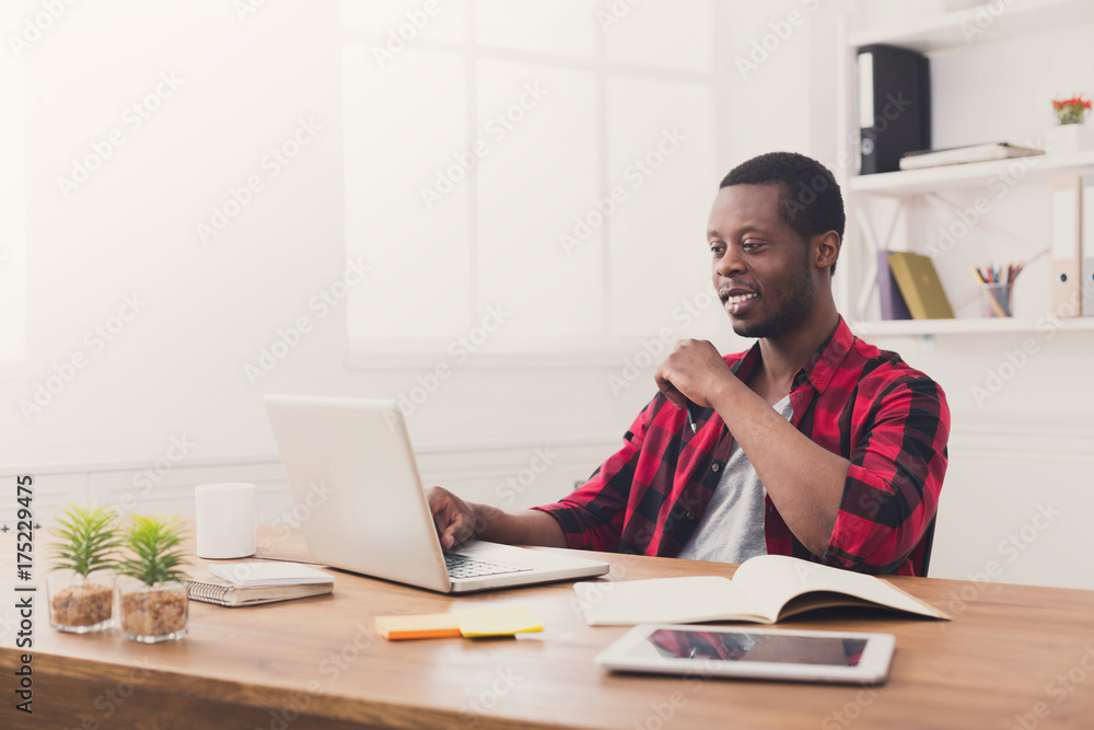 Happy black businessman in casual office, work with laptop