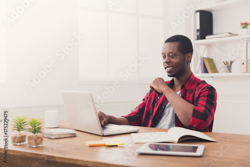 Happy black businessman in casual office, work with laptop