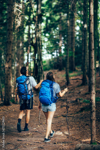 Hiking couple. Young couple with backpacks walking through the forest  