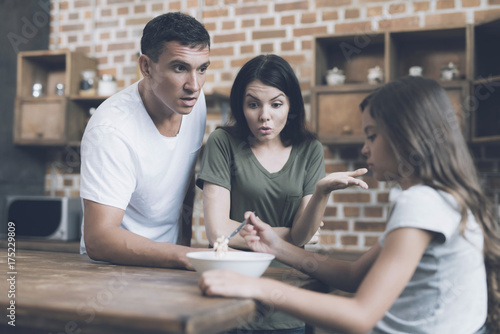A man and a woman reproach a girl with the fact that she does not want to eat, and she only looks sad at the plate