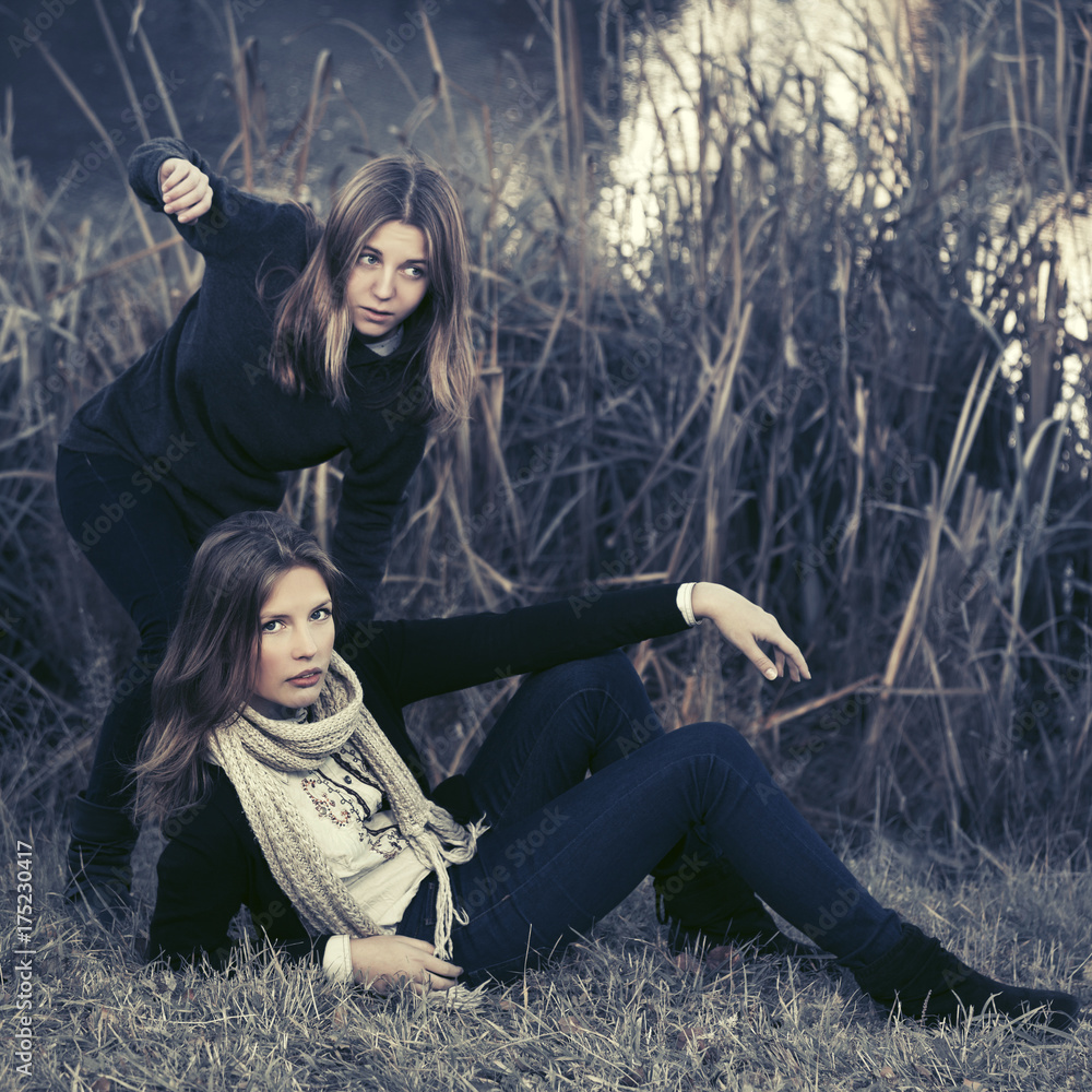 Two young fashion girls by the lake in autumn park Two young fashion girls by the lake in autumn park