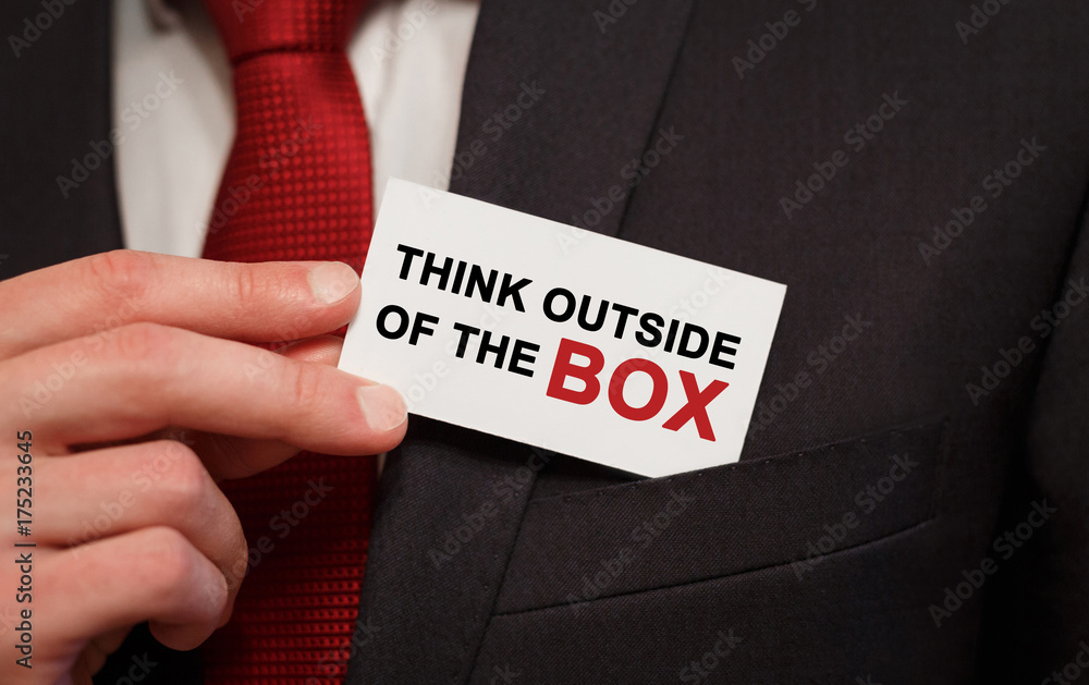 Businessman putting a card with text Think Outside of the Box in the pocket Businessman putting a card with text Think Outside of the Box in the pocket