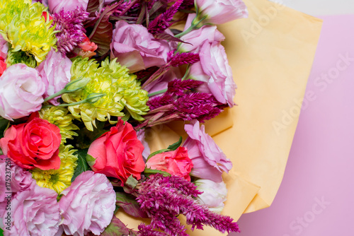 A beautiful bouquet of pink eustoms, a yellow chrysanthemum, a red and pink rose, on a pink background photo