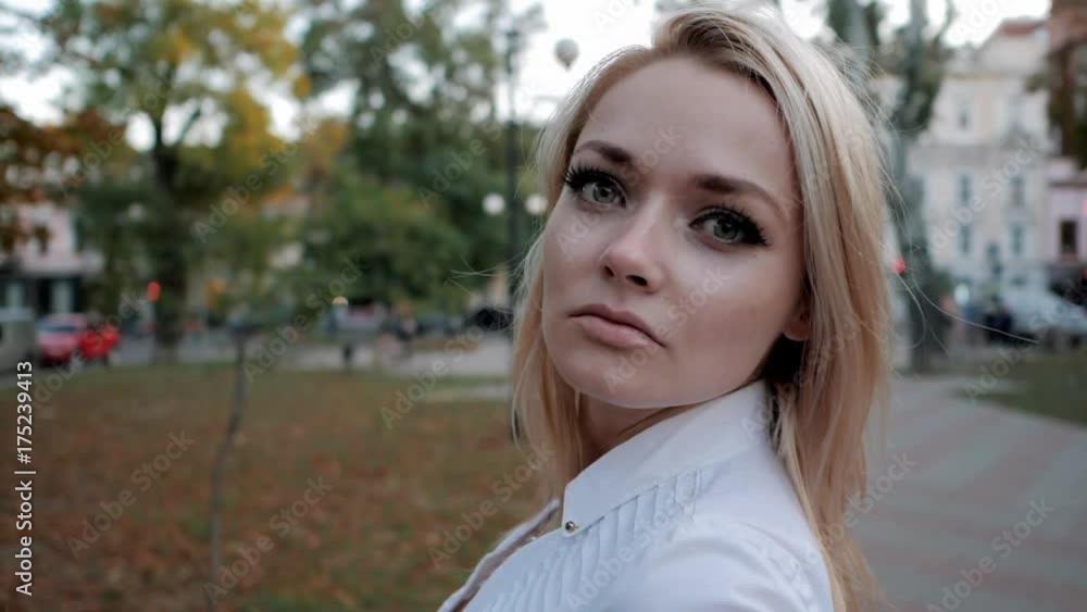 Portrait of young happy blonde businesswoman in the city. Slow motion. Beautiful girl in white sexy shirt turns around and smiles in the street. Fluttering hair. Portrait of young happy blonde businesswoman in the city. Slow motion. Beautiful girl in white sexy shirt turns around and smiles in the street. Fluttering hair.