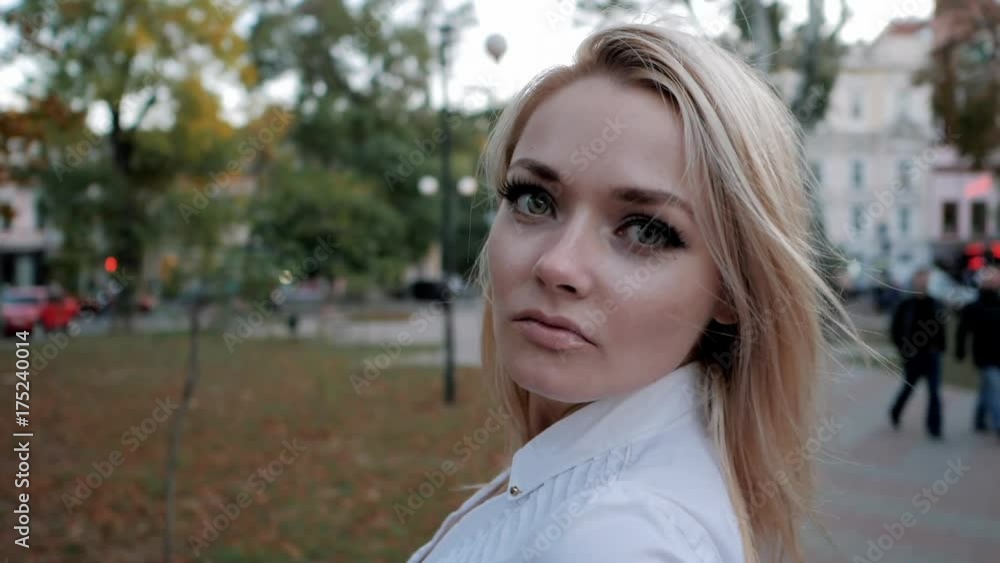 Portrait of young happy blonde businesswoman in the city. Slow motion. Beautiful girl in white sexy shirt turns around and smiles in the street. Fluttering hair. Portrait of young happy blonde businesswoman in the city. Slow motion. Beautiful girl in white sexy shirt turns around and smiles in the street. Fluttering hair.
