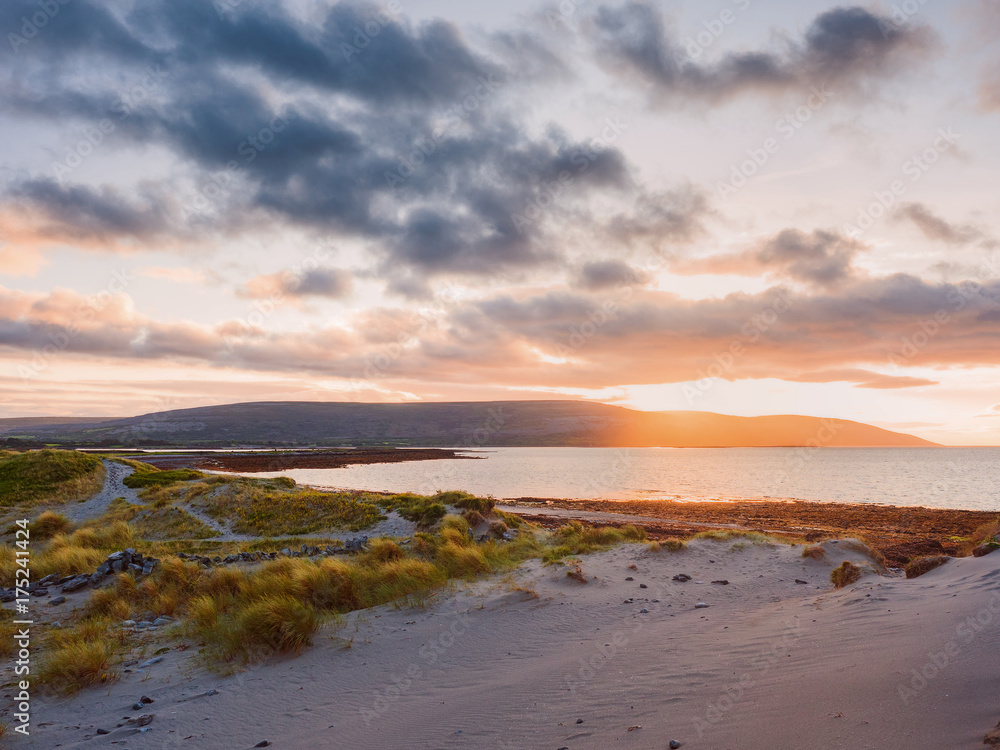 Sunset over the Atlantic ocean, the Burren National park area. Sand dunes and coast line.