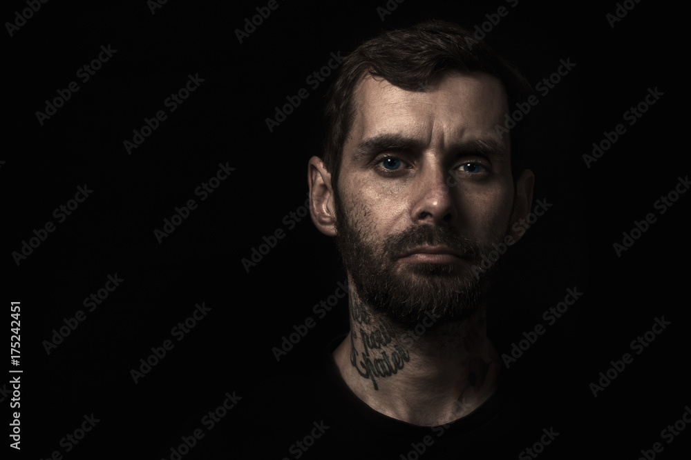 advertising portrait of young brutal man with a big beard and a manly look, on a black background in the right side of the frame