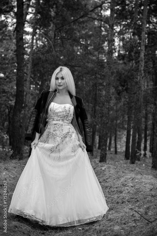 A runaway bride in a wedding dress and a leather jacket in the forest. Difficulties at the wedding. Fashionable girl in grunge style