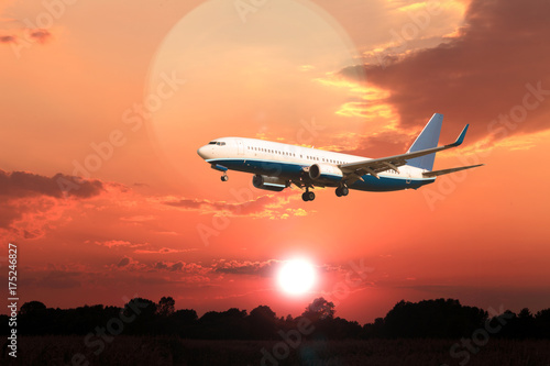 Odrzutowy samolot pasażerski na tle zachodzącego słońca.