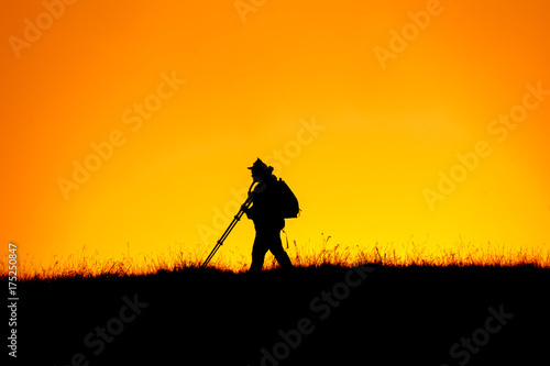 Silhouette of photographer walking top of mountain at sunset time.Sky background.