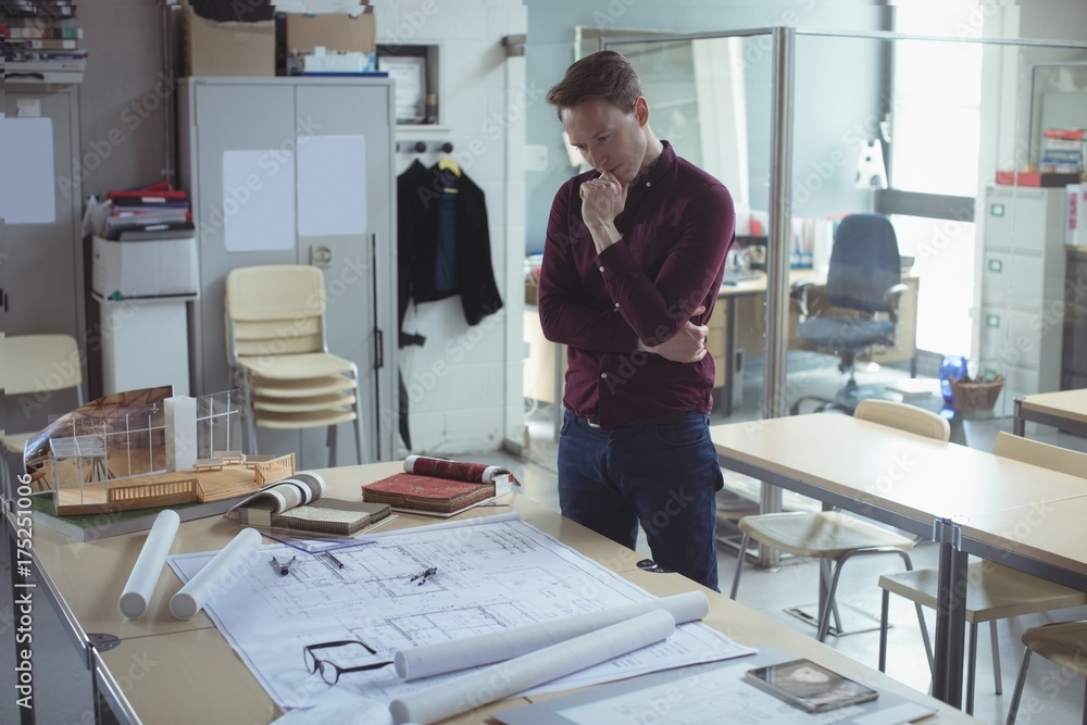 Thoughtful architect looking at blueprint Thoughtful architect looking at blueprint