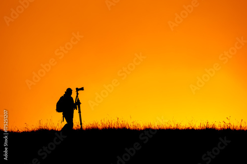 Silhouette of photographer walking top of mountain at sunset time.Sky background.
