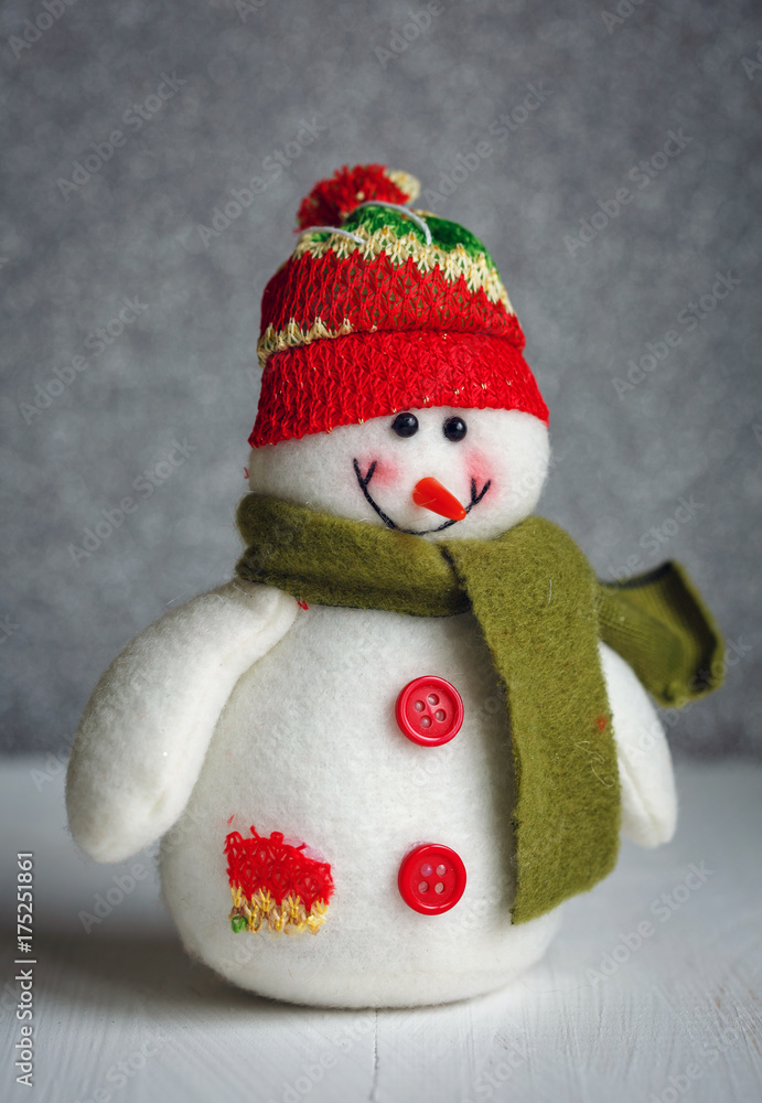 Smiling snowman toy dressed in scarf and cap on abstract bokeh background. Smiling snowman toy dressed in scarf and cap on abstract bokeh background.