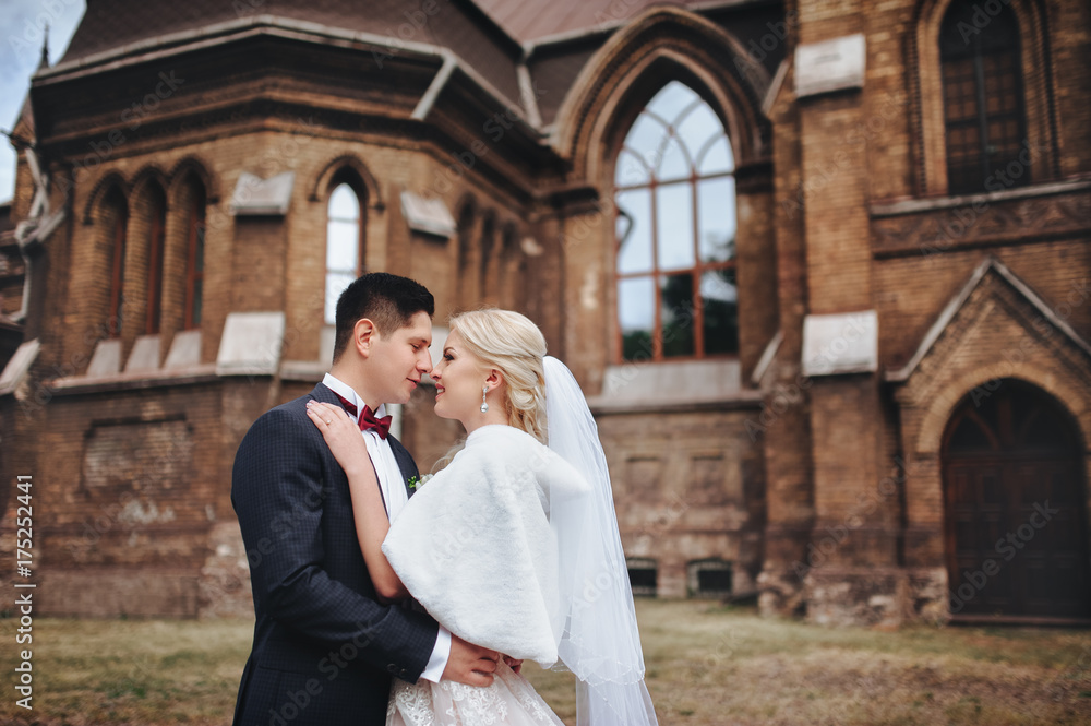 The newlyweds are standing on the background of the catalytic church. Catholic temple. Wedding concept. The newlyweds are standing on the background of the catalytic church. Catholic temple. Wedding concept.