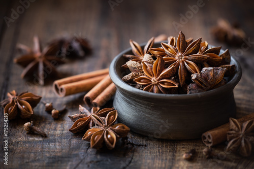 Anise stars in a black bowl with cinnamon sticks and cloves. Winter seasonal baking concept with copy space for your text