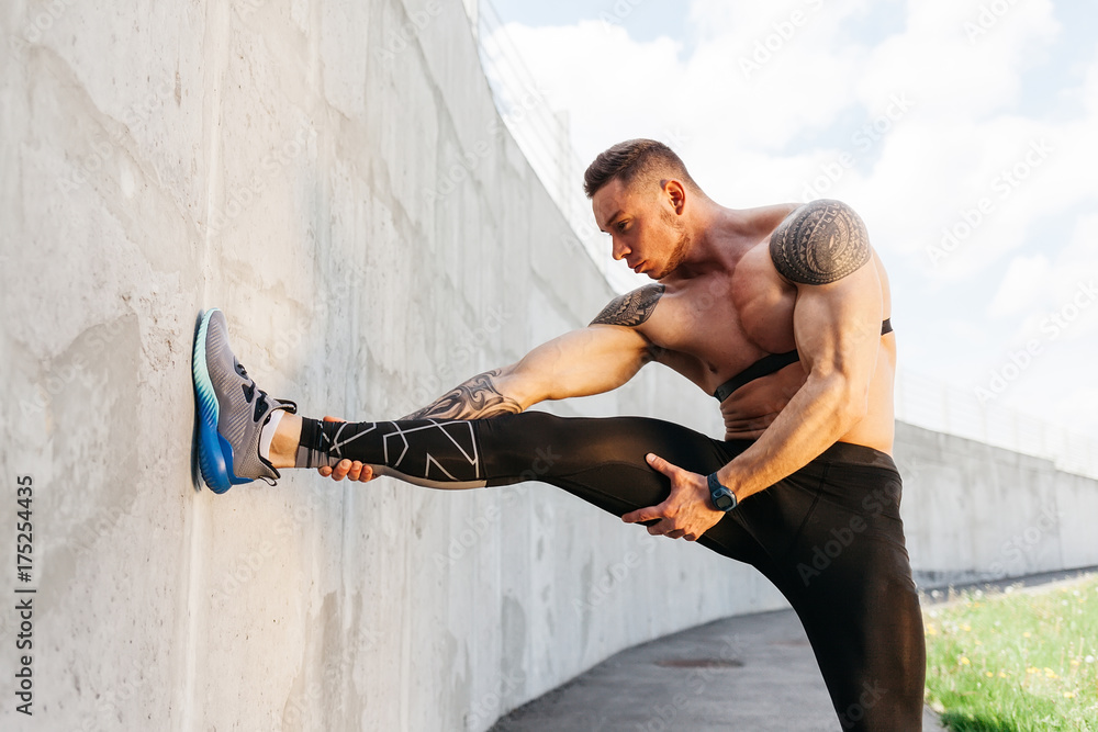 Obraz Portret sportowca trenującego nogi w szarym tle ściany