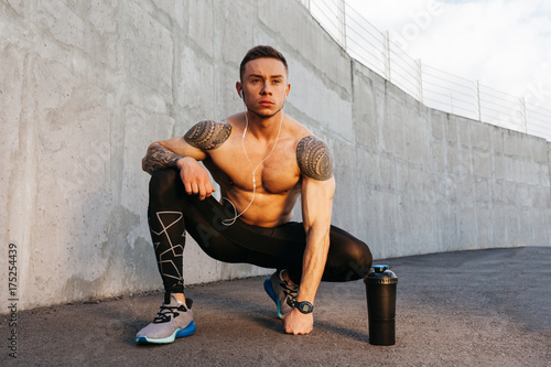 Portrait of sporty young man with a bare throat in gray wall background photo