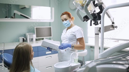 A woman stomotologist talking to a girl with a patient in a dental office photo