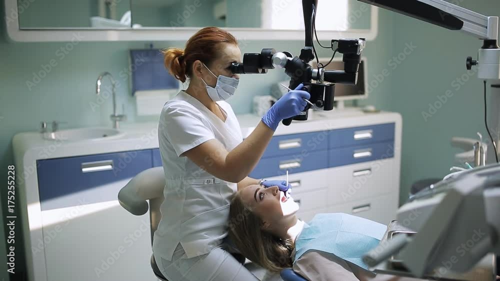 Female dentist with dental tools - microscope, mirror and probe treating patient teeth at dental clinic office. Medicine, dentistry and health care concept. Dental equipment Female dentist with dental tools - microscope, mirror and probe treating patient teeth at dental clinic office. Medicine, dentistry and health care concept. Dental equipment