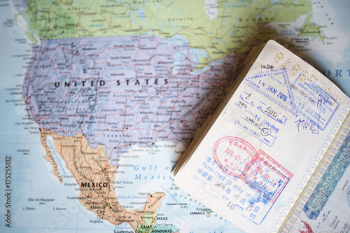 Obraz na płótnie (Selective focus) Close-up view of a passport with entry stamps on a blurred geographical map of the world. The map shows the United States an Mexico w salonie