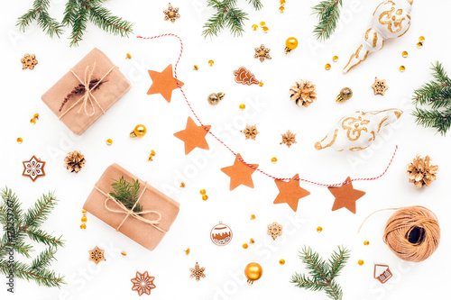 Golden christmas decorations, christmas gift, golden pine cone, paper, spruce branches on white background. Flat lay, top view.