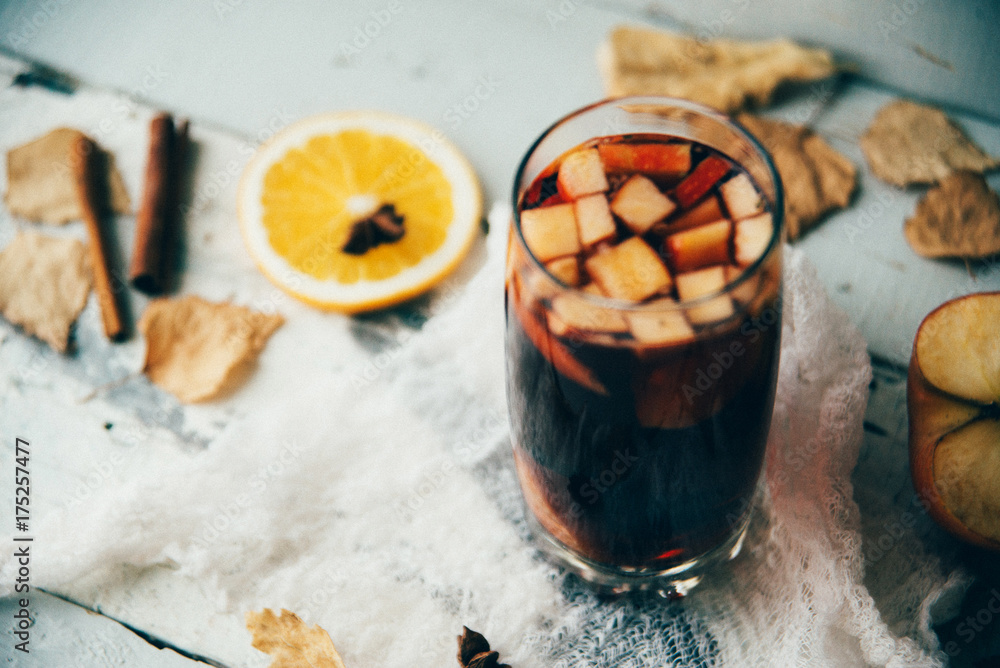 Hot mulled wine in a glass with orange slices, anise and cinnamon sticks, star cookies on vintage wood table. Christmas or winter warming drink with recipe ingredients around Hot mulled wine in a glass with orange slices, anise and cinnamon sticks, star cookies on vintage wood table. Christmas or winter warming drink with recipe ingredients around