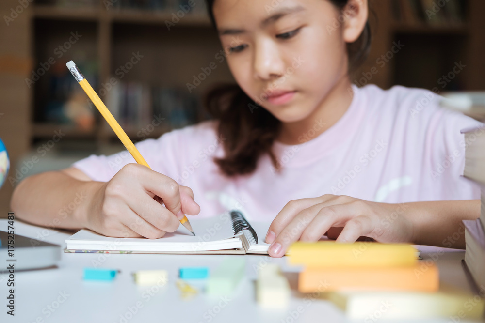 Girl reading and writing in library of school. Girl reading and writing in library of school.