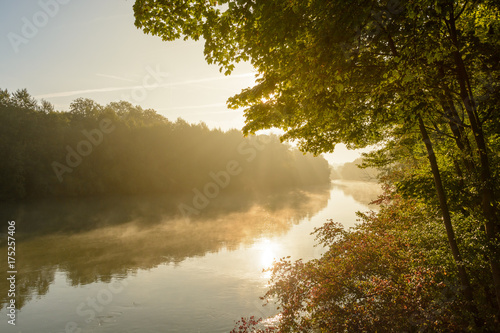 Fog patches floating over the still water of the river Marne at sunrise.