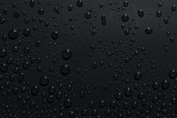Closeup of black raindrops on dark surface, abstract background