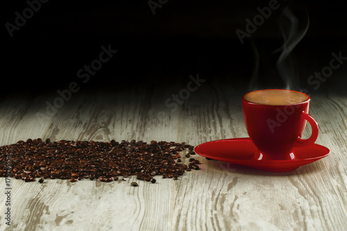 Coffee in the red cup on old boards with coffee beans