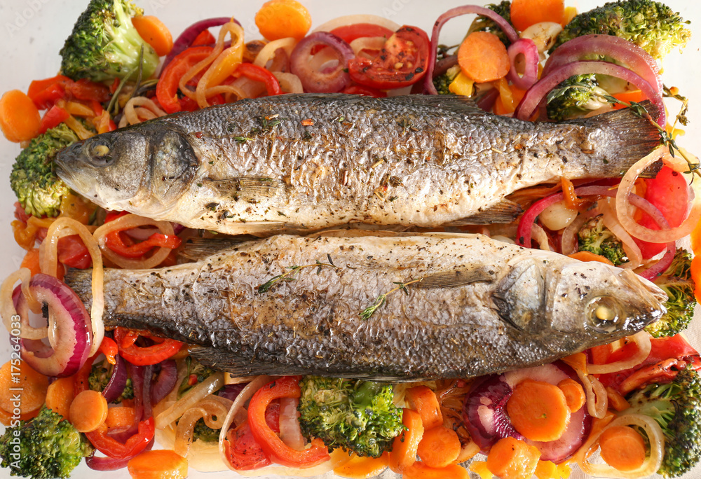 Tasty baked fish with vegetable garnish, top view Tasty baked fish with vegetable garnish, top view