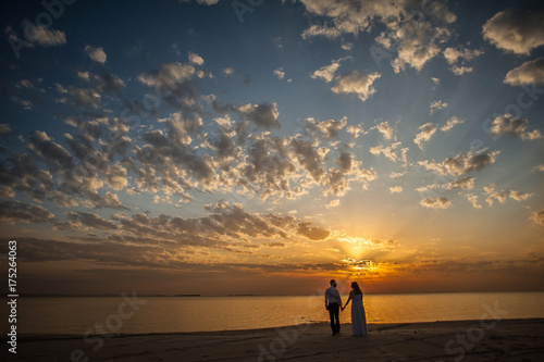 Bride and groom, newlyweds, honeymoon on the beach sunset sun