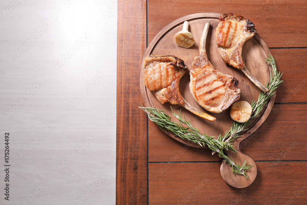 Wooden board with delicious ribs on table Wooden board with delicious ribs on table