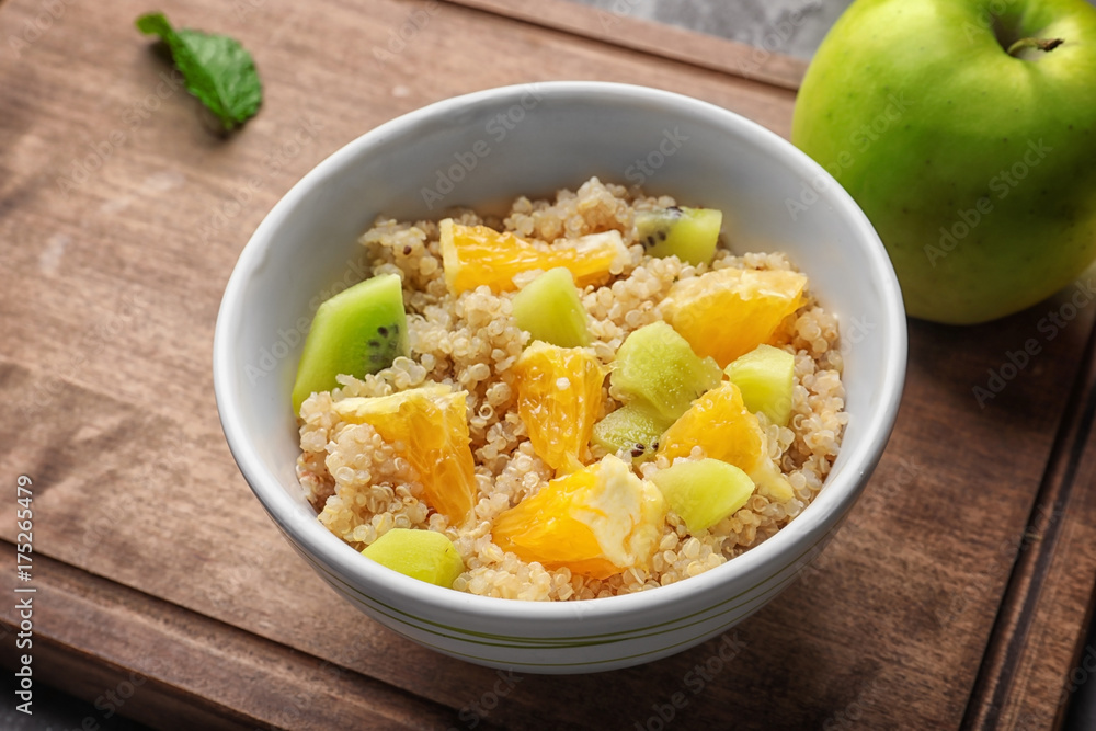 Tasty quinoa with fruits in bowl on wooden board Tasty quinoa with fruits in bowl on wooden board