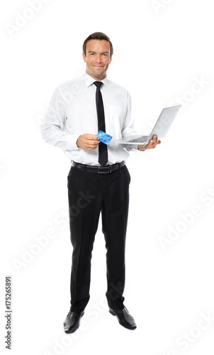 Young businessman holding credit card while using laptop on white background