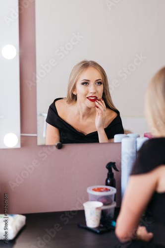 Beautiful woman in black dress with professional make up in beauty salon