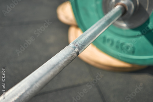 Close-up. Sport equipment. Outdoors. Green colors. Sports ground. Bar with weights