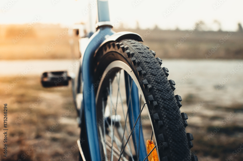 the front wheel of the Bicycle at sunset with sun flare the front wheel of the Bicycle at sunset with sun flare