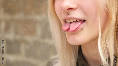 bodimodification, portrait of a girl with face piercings and tunnels in the ears. a girl with a split tongue. shows the language. 4k, slow-motion shooting, copying space