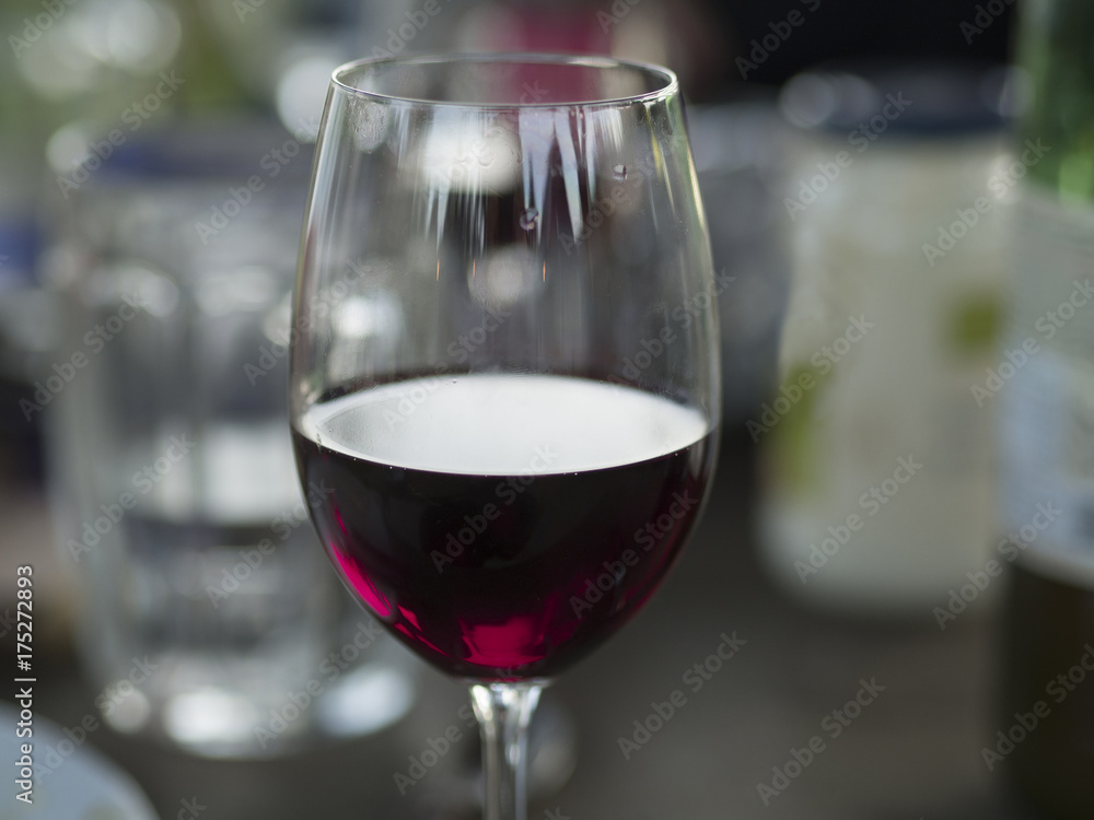 close up glass of red wine bokeh table with bottles and food