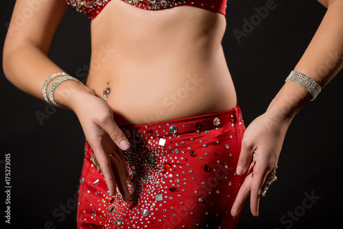 Image of belly dancer performing belly dance on black background.