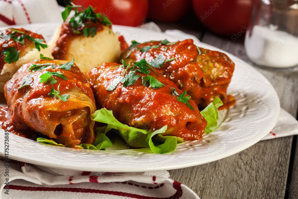 Stuffed cabbage with meat and rice served with boiled potatoes and tomato sauce