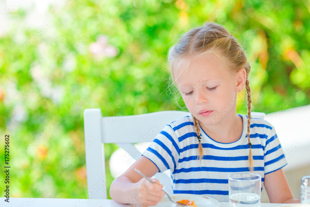 Adorable little girl having breakfast at cafe with sea view early in the morning Adorable little girl having breakfast at cafe with sea view early in the morning