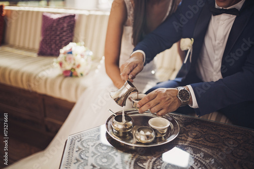 Bride and groom laughing and drinking coffee in an oriental coffee shop photo