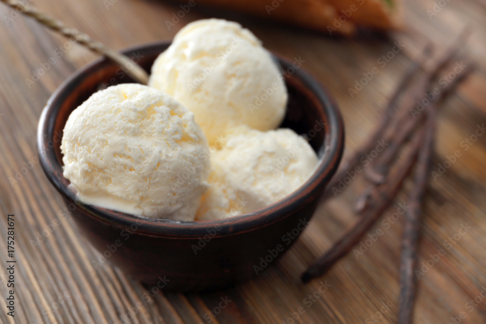 Bowl with yummy vanilla ice cream on wooden table