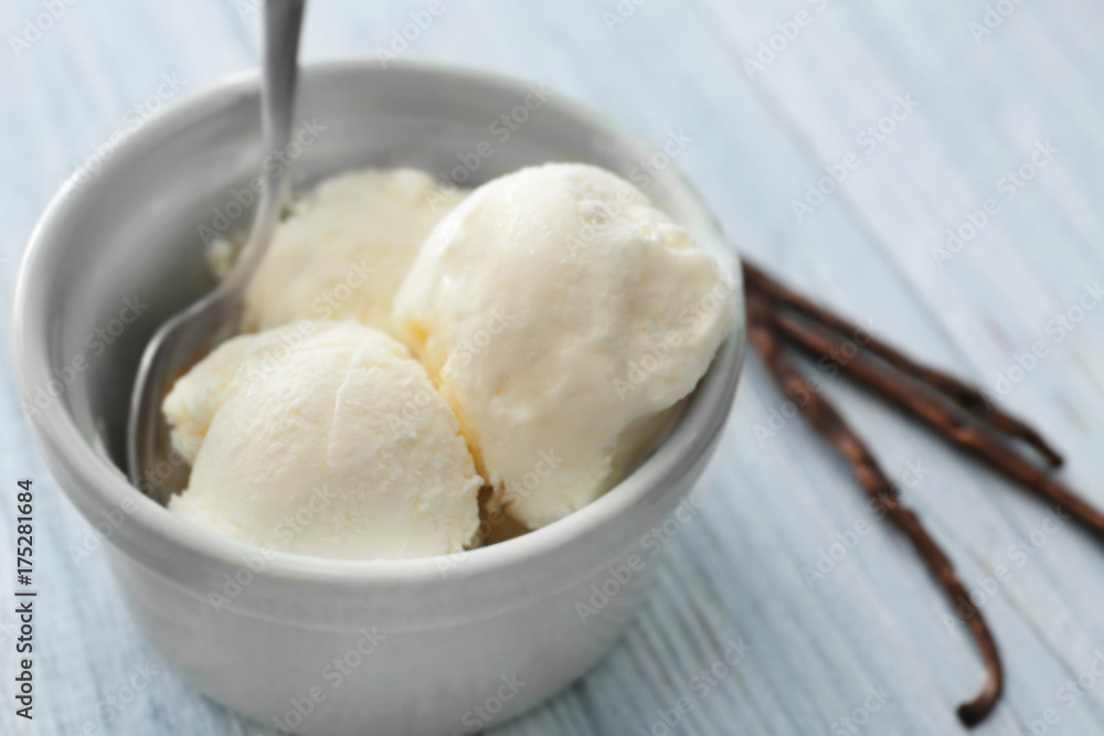 Bowl with yummy vanilla ice cream on wooden table