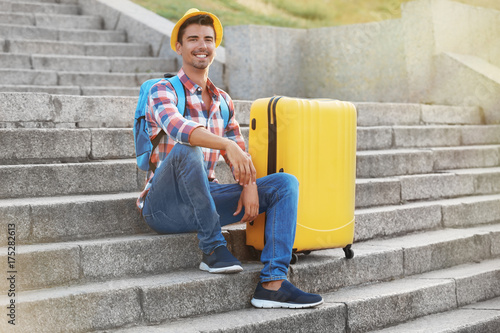 Young man with suitcase sit...